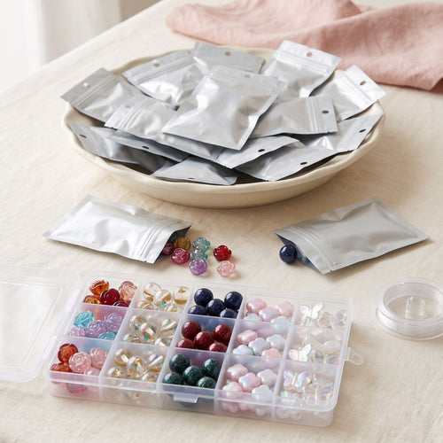 A dish piled high with silver blind bags, the clear bead box full of sorted beads in front